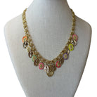 A gold-tone multi-strand necklace with small oval religious medallions in assorted colors, displayed on a light beige fabric mannequin bust against a white background.