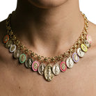 A gold-tone chain necklace with multiple oval Miraculous Medal charms in assorted colors, shown worn on a person's neck against a plain white background.