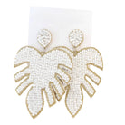 Leaf-shaped beaded earrings with gold and white design on a white background
