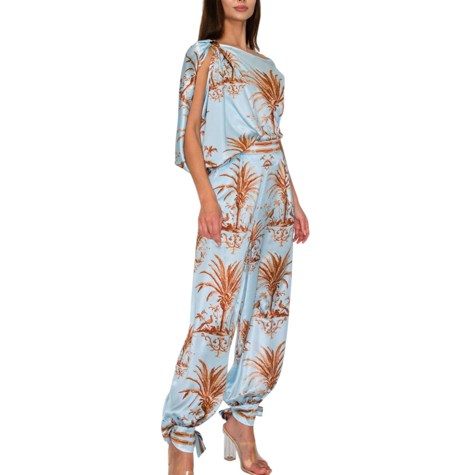 Woman wearing a light blue jumpsuit with brown floral patterns on a white background