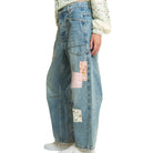 Blue jeans with patchwork design worn by a person on a white background