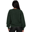A woman viewed from the back wearing a dark forest green crewneck sweatshirt and black pants, set against a plain white background.