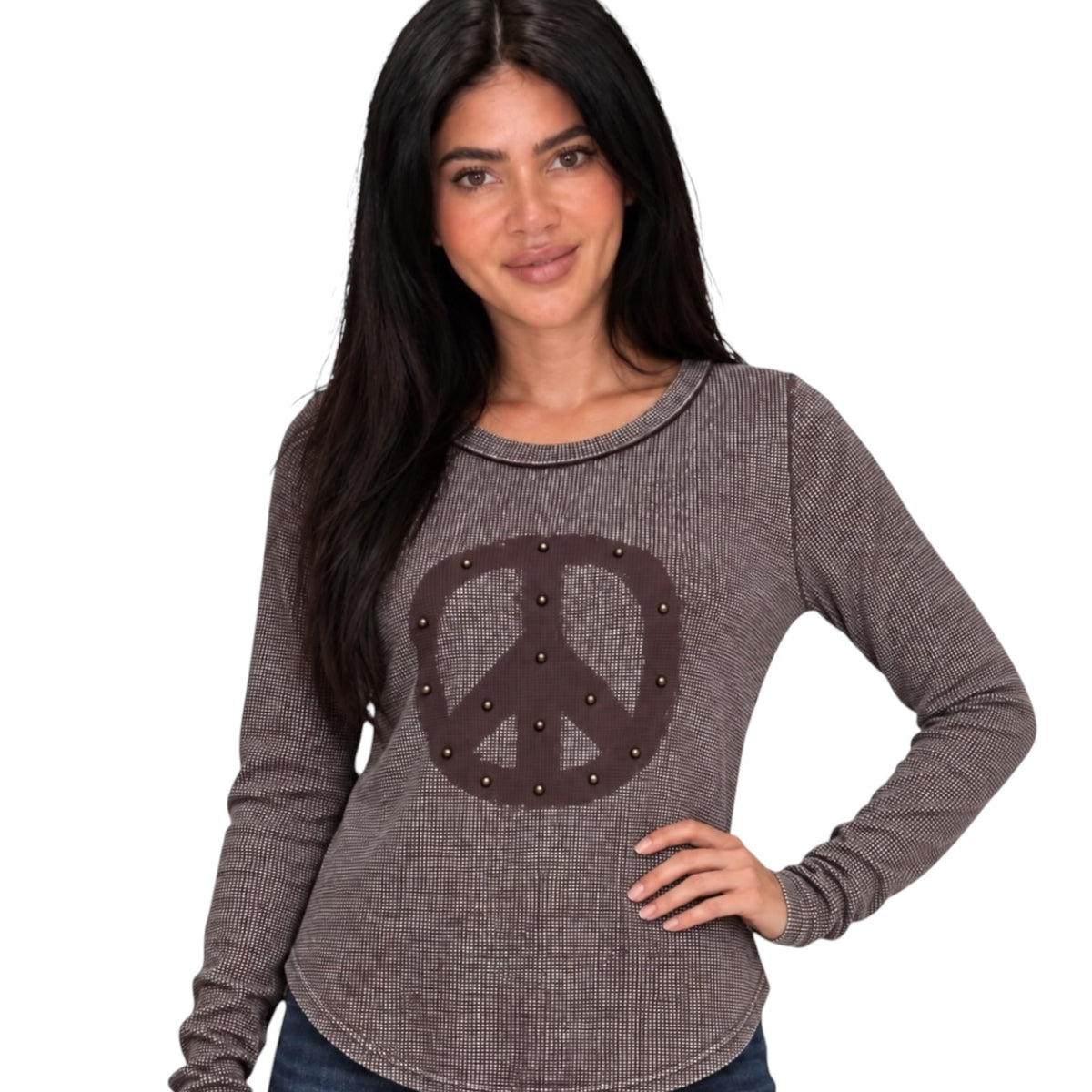 A woman wearing a brown waffle-knit long-sleeve shirt with a large peace sign graphic on the front, embellished with small metallic studs, set against a plain white background.