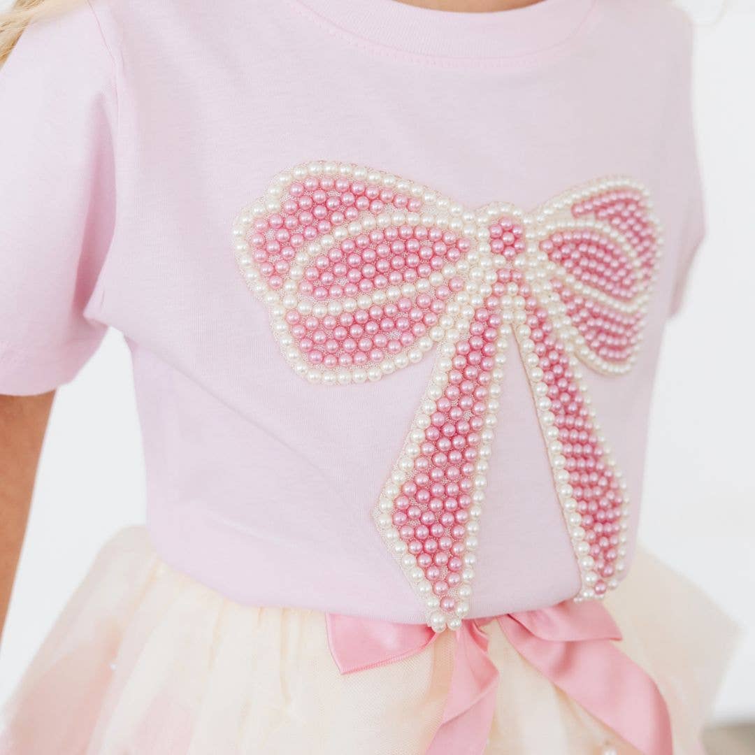 Pink top with a decorative bow made of pearls on a white background