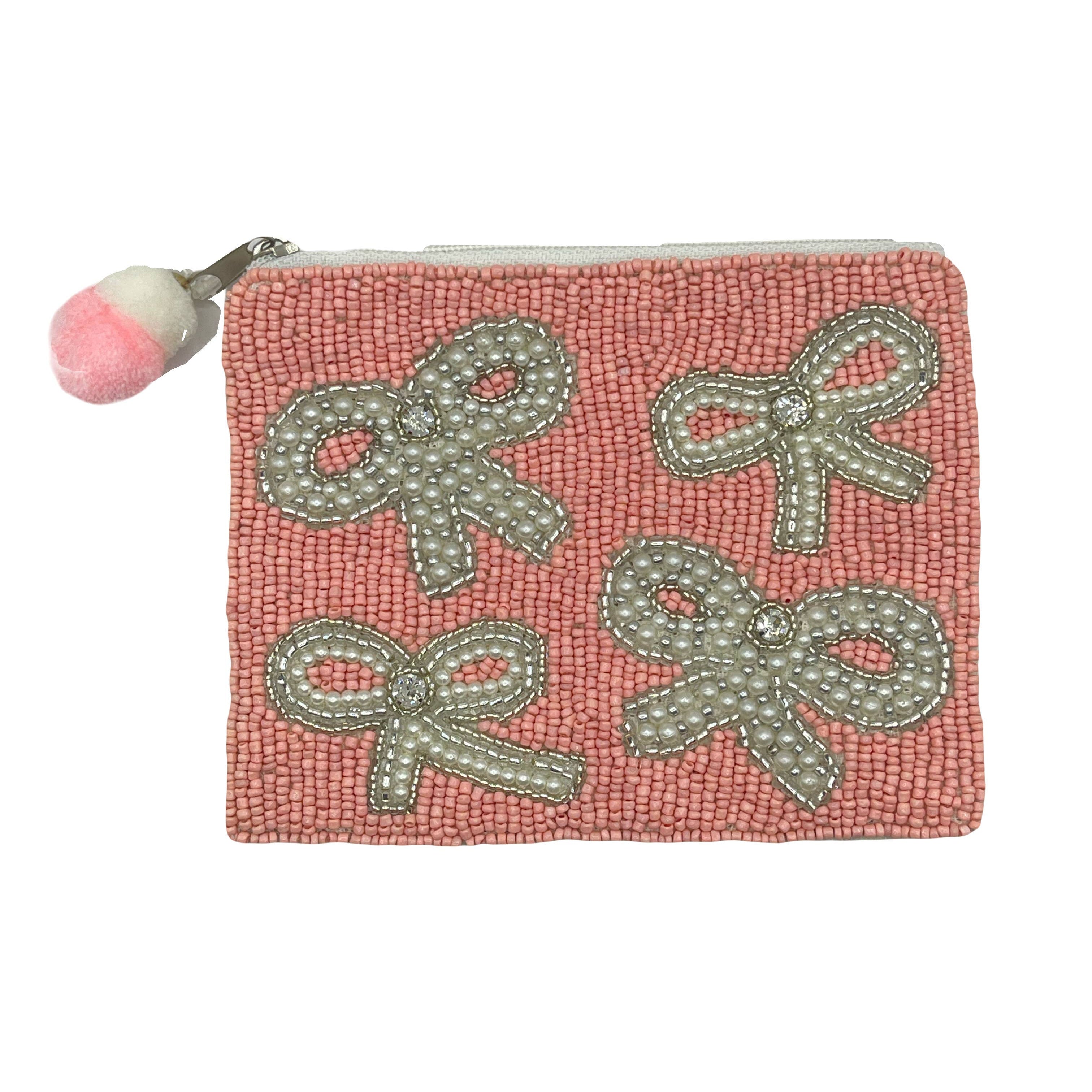Pink beaded pouch with bow designs and a pom-pom on a white background