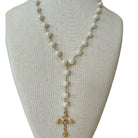 A gold and white pearl necklace displayed on a beige fabric jewelry bust against a white background.