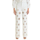 White pants with brown floral patterns worn by a person on a white background