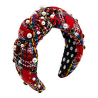 A knotted fabric headband featuring a red and black holiday plaid pattern with white snowflake designs, decorated with faux pearls and small metallic beads, shown on a plain white background.
