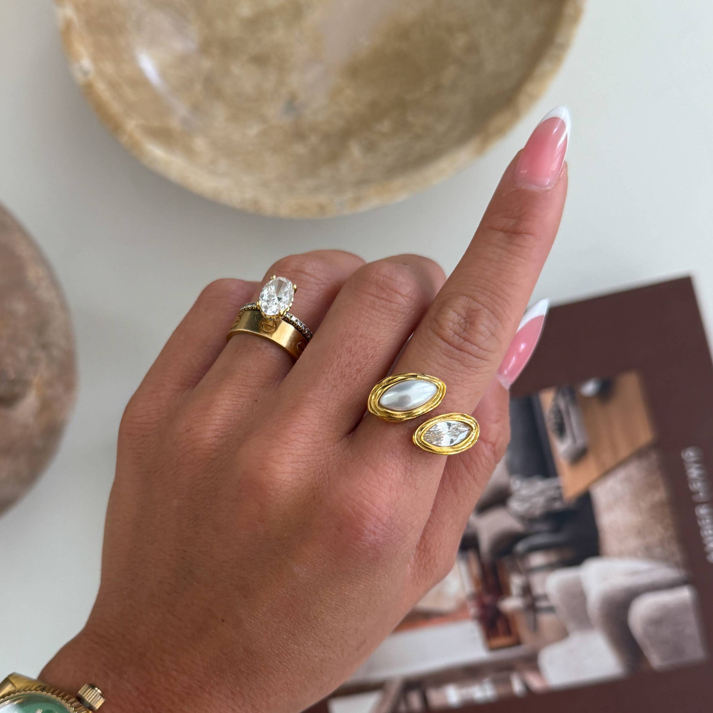 Hand wearing a gold watch and rings with a blurred background