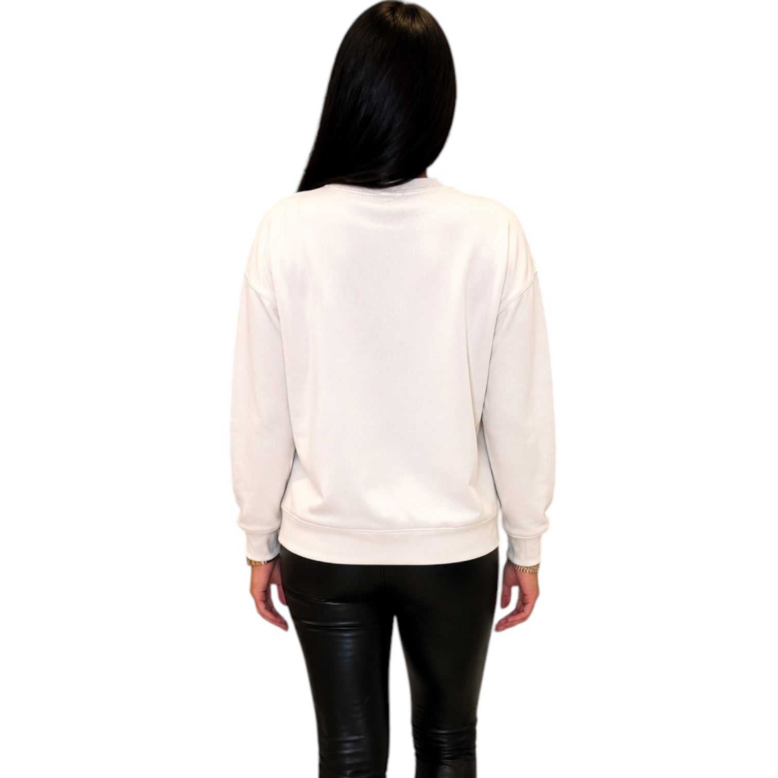 A woman viewed from behind wearing a plain white crewneck sweatshirt and black pants, set against a solid white background.