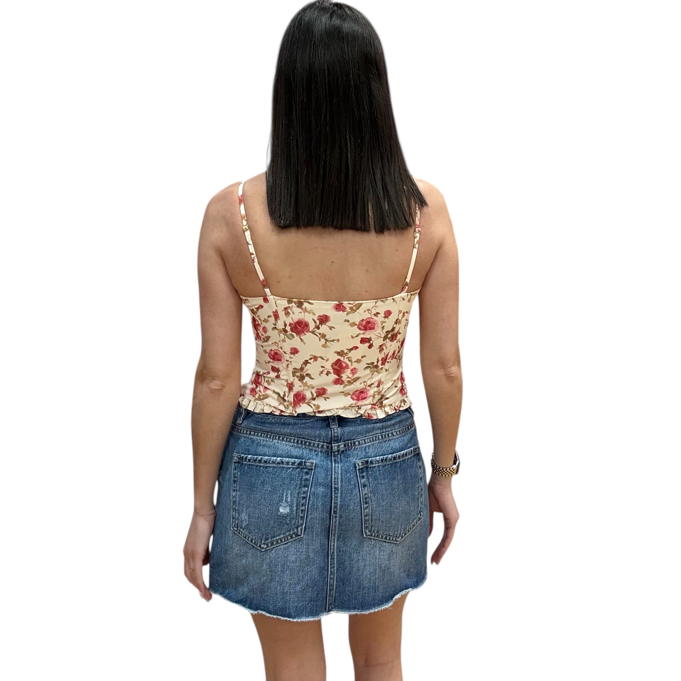 Woman wearing a floral top and denim skirt on a white background