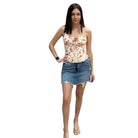 Woman wearing a floral top and denim skirt on a white background