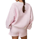 Person wearing a pink and white checkered outfit on a white background