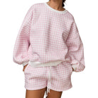 a woman wearing a pink gingham set on white background