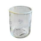 Clear glass tumbler with embossed designs on a white background