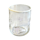 Clear glass tumbler with embossed designs on a white background