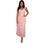 a woman wearing a pink floral dress with ruffles on white background