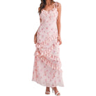 a woman wearing a pink floral dress with ruffles on white background
