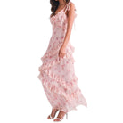 a woman wearing a pink floral dress with ruffles on white background
