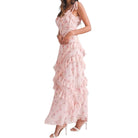 a woman wearing a pink floral dress with ruffles on white background