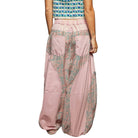 Person wearing a patterned top and pink patchwork pants on a white background