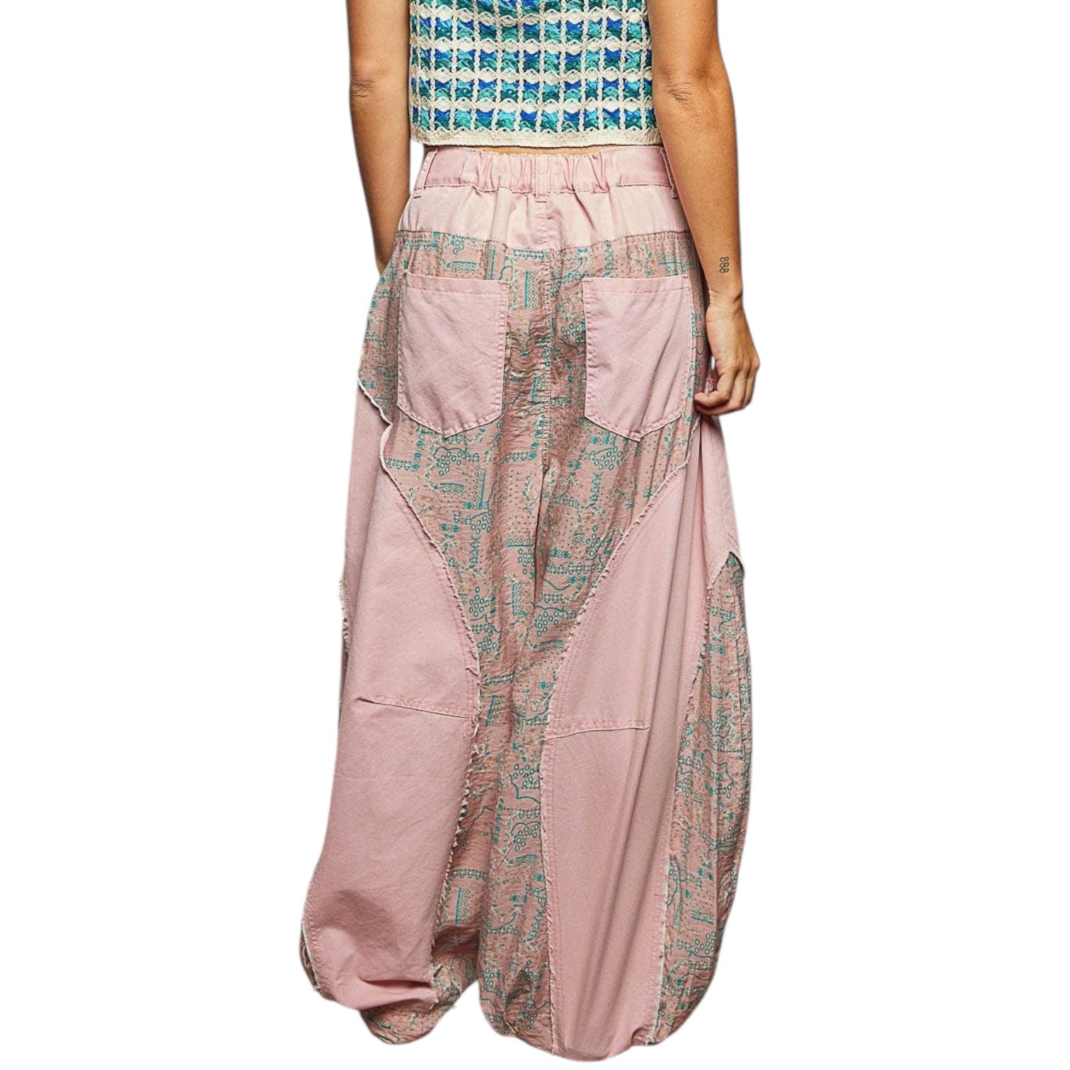Person wearing a patterned top and pink patchwork pants on a white background
