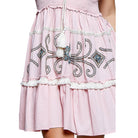 Pink dress with intricate white embroidery on a white background