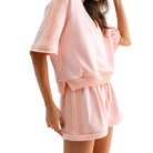 Pink outfit with cable knit details on a white background