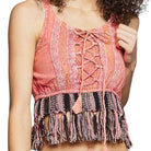 Woman wearing a pink lace-up top with fringes on a white background