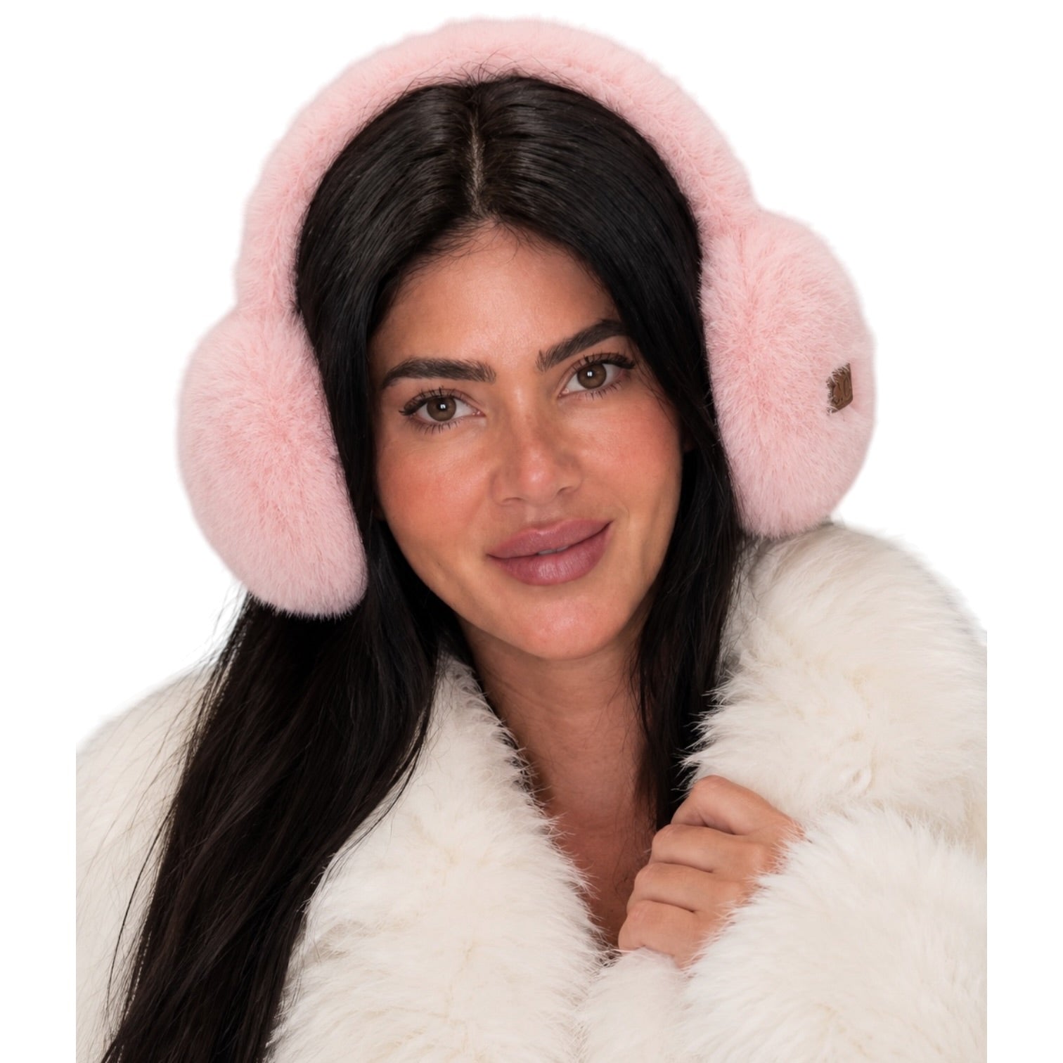 A woman wearing fluffy light pink earmuffs and a white faux-fur coat against a plain white background.