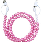 Pink beaded cable coiled on a light wooden surface with a laptop in the background.