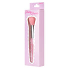 A pink makeup brush in its original retail packaging. The brush features a pink bristle head, a silver metallic handle, and a handle decorated with pink faux pearls.