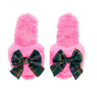 A pair of fluffy pink slip-on slippers with large green tartan plaid bows on the front, shown against a plain white background.