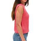 Woman wearing a pink sleeveless crochet top on a white background