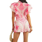 a woman wearing a pink patterned short set on white background