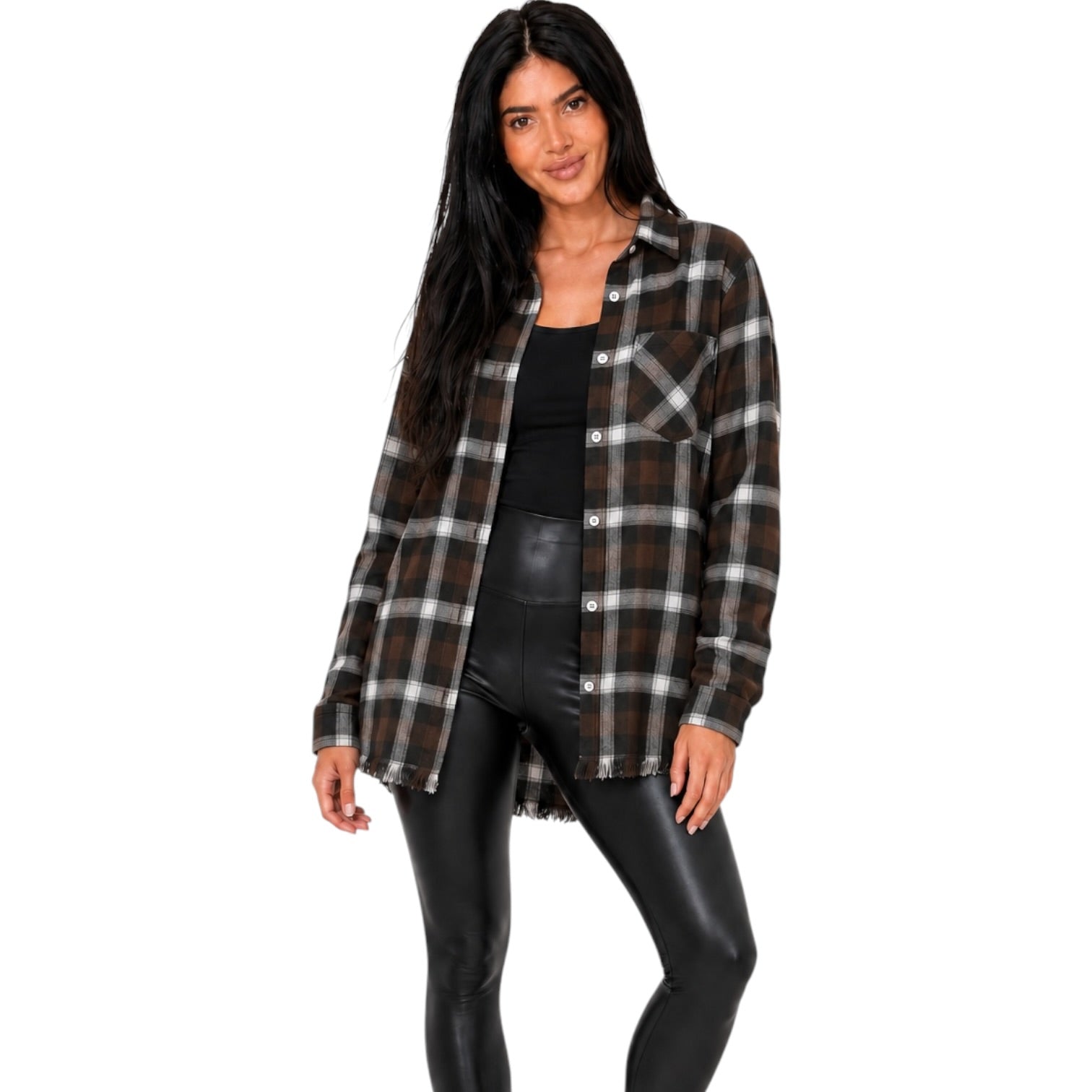 A woman modeling a brown, black, and white plaid button-up flannel shirt over a black top and black faux-leather pants, set against a plain white background.