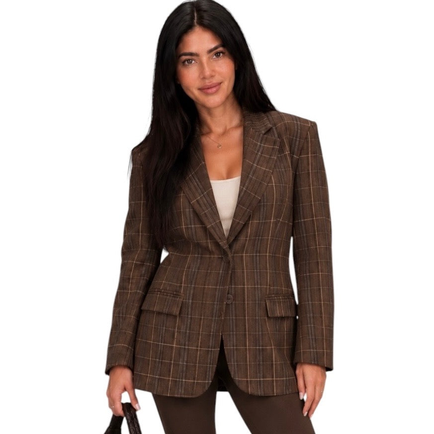 A woman modeling a brown plaid blazer with a single-breasted design, worn over a white top and brown pants, against a plain white background.