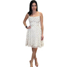 Woman wearing a white dress with black polka dots on a white background