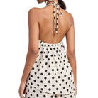 Woman wearing a polka dot halter top with a white background