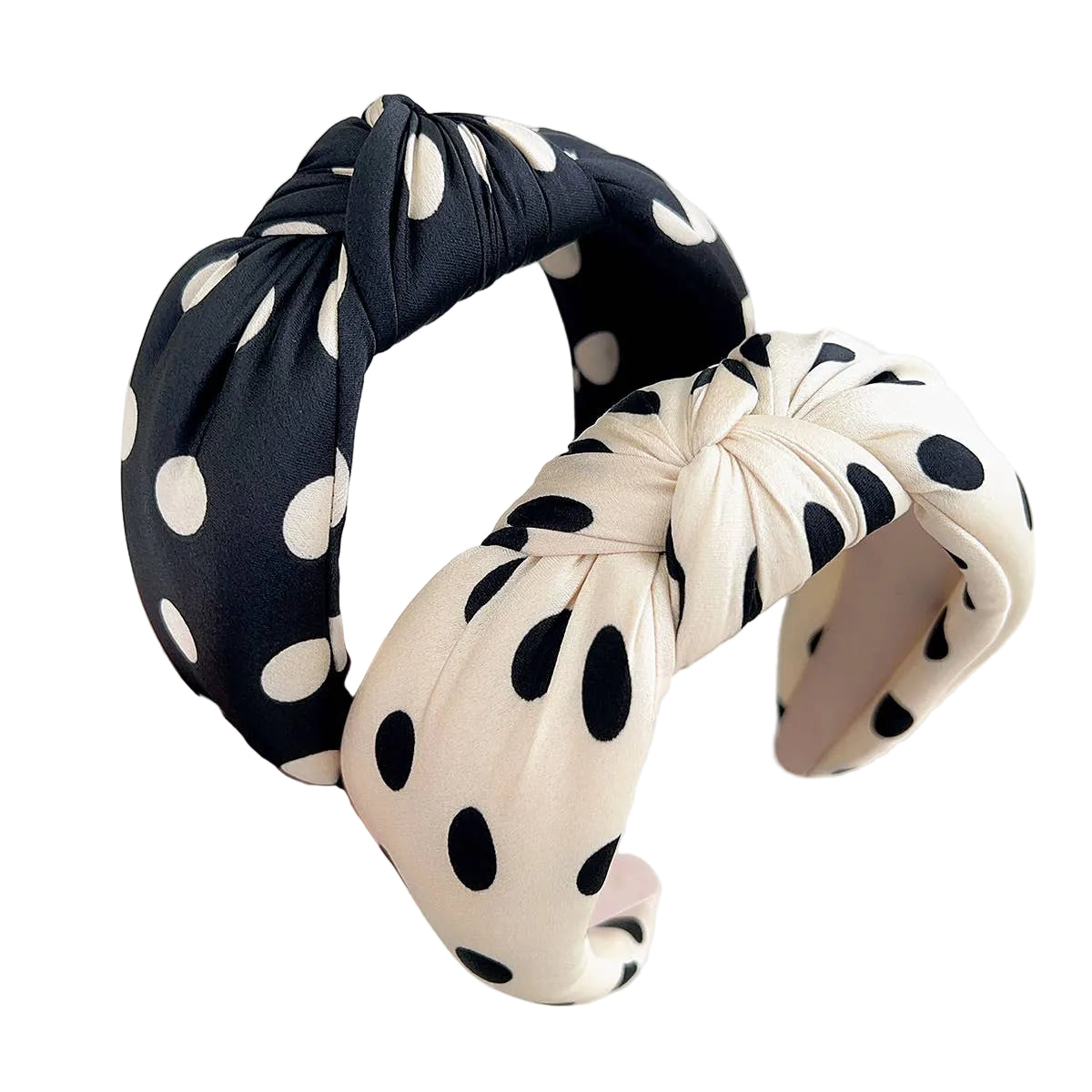 Two polka dot headbands, one black and white, one beige and black, held by a hand against a light background.