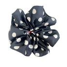 Black scrunchie with white polka dots held by a hand against a light background