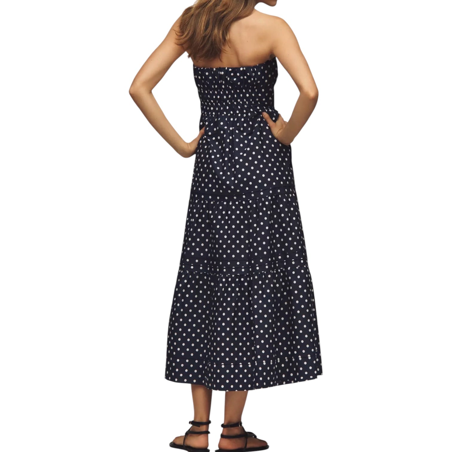 Woman wearing a black strapless dress with white polka dots on a white background