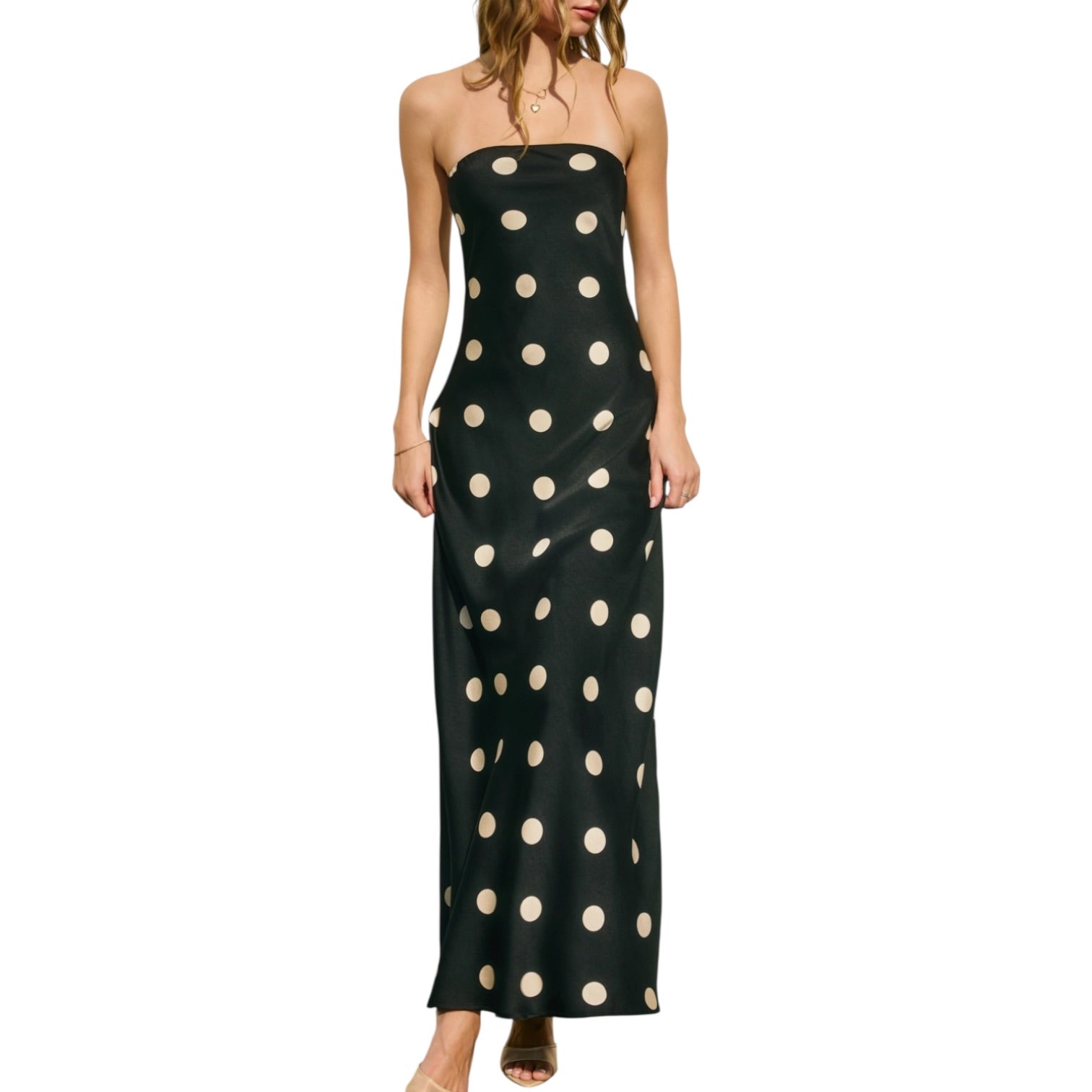 Woman wearing a black strapless dress with white polka dots on a white background