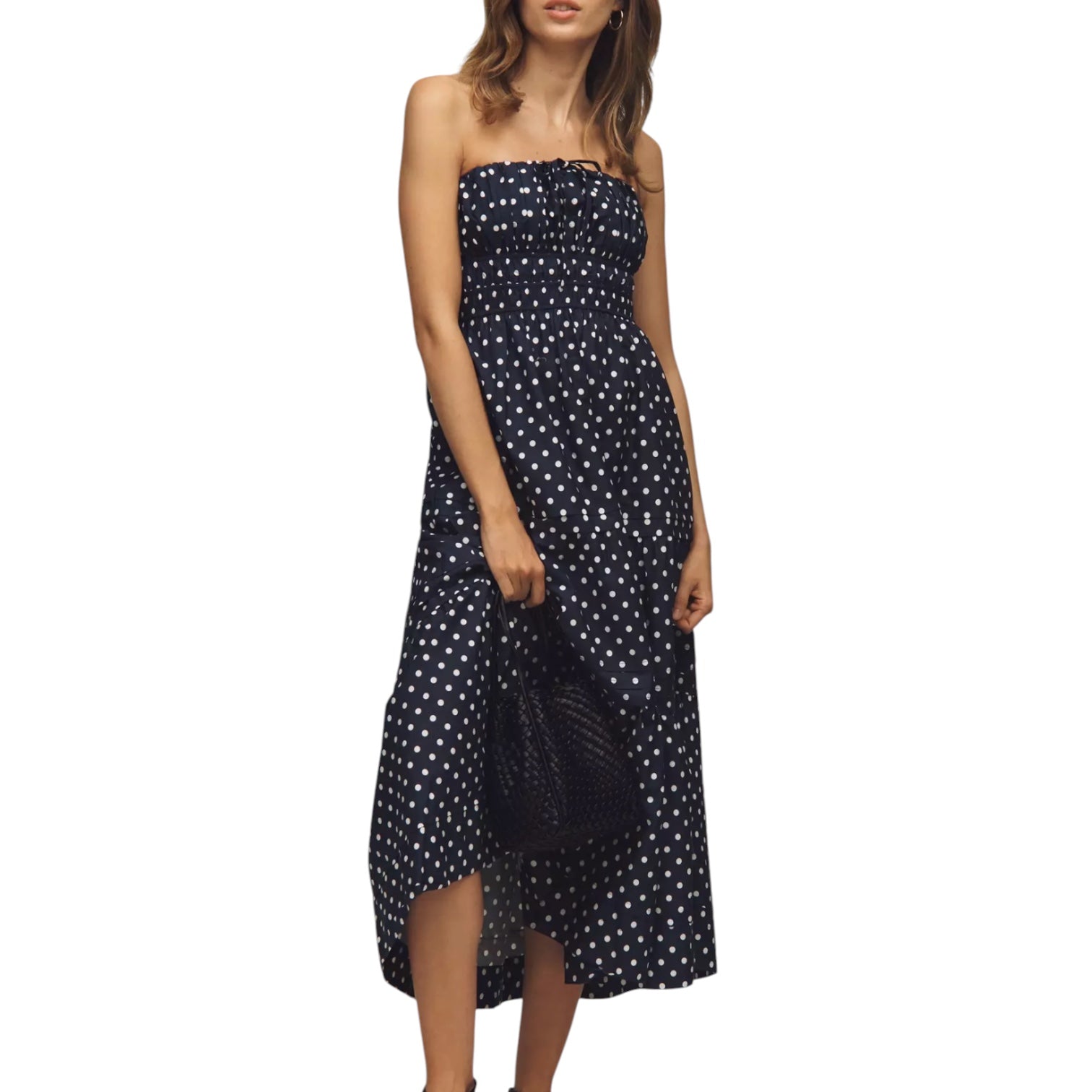 Woman wearing a strapless black dress with white polka dots on a white background