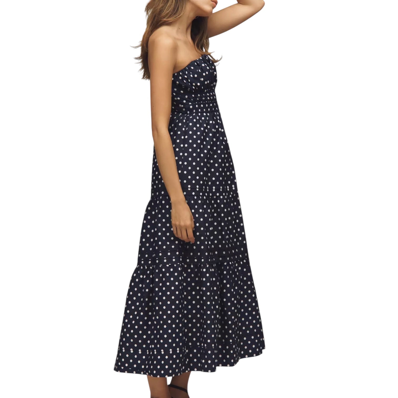 Woman wearing a navy blue strapless dress with white polka dots on a white background