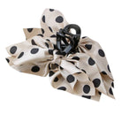 A large hair claw clip decorated with a voluminous beige satin bow featuring black polka dots, set against a plain white background.