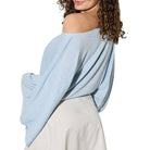 Light blue off-shoulder top worn by a person on a white background