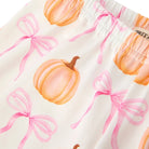 Close-up of a white fabric garment with a watercolor-style print of orange pumpkins and pink bows, showing an elastic waistband.