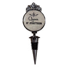 A gothic-style metal wine bottle stopper featuring a circular glass insert with the text 'Queen of Everything' in black script and serif fonts, topped with a silver ornate crown design, and fitted with a black and silver threaded stopper.