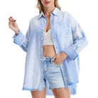 Woman wearing a blue striped shirt over a white top and denim shorts on a white background